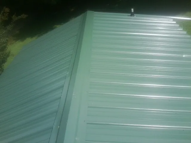 New green metal panels meeting at the ridge of a roof — Flat Roof Repair work by our crew in Hot Springs National Park