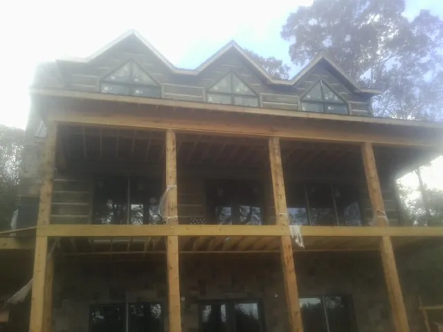 Dormers and porch framing on a large log home under construction — Roof Coating work by our crew in Hot Springs National Park