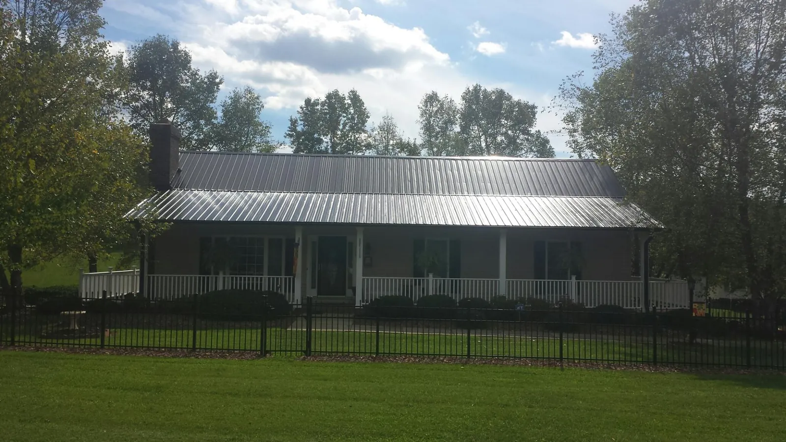 Gray metal roof on a brick ranch with a full width front porch — Gutter Guard Installation work by our crew in Hot Springs National Park