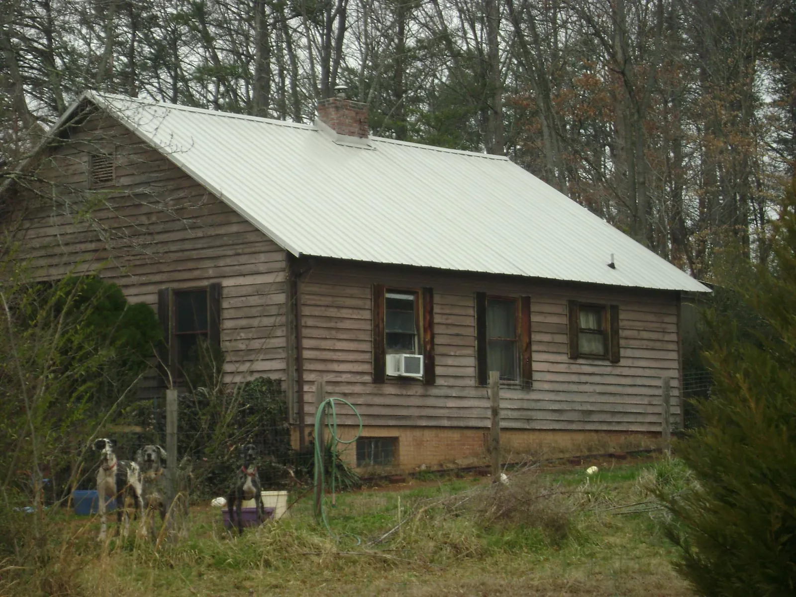White metal roof on an old wood sided farmhouse, from a Asphalt Shingle Roof Repair job in Hot Springs National Park