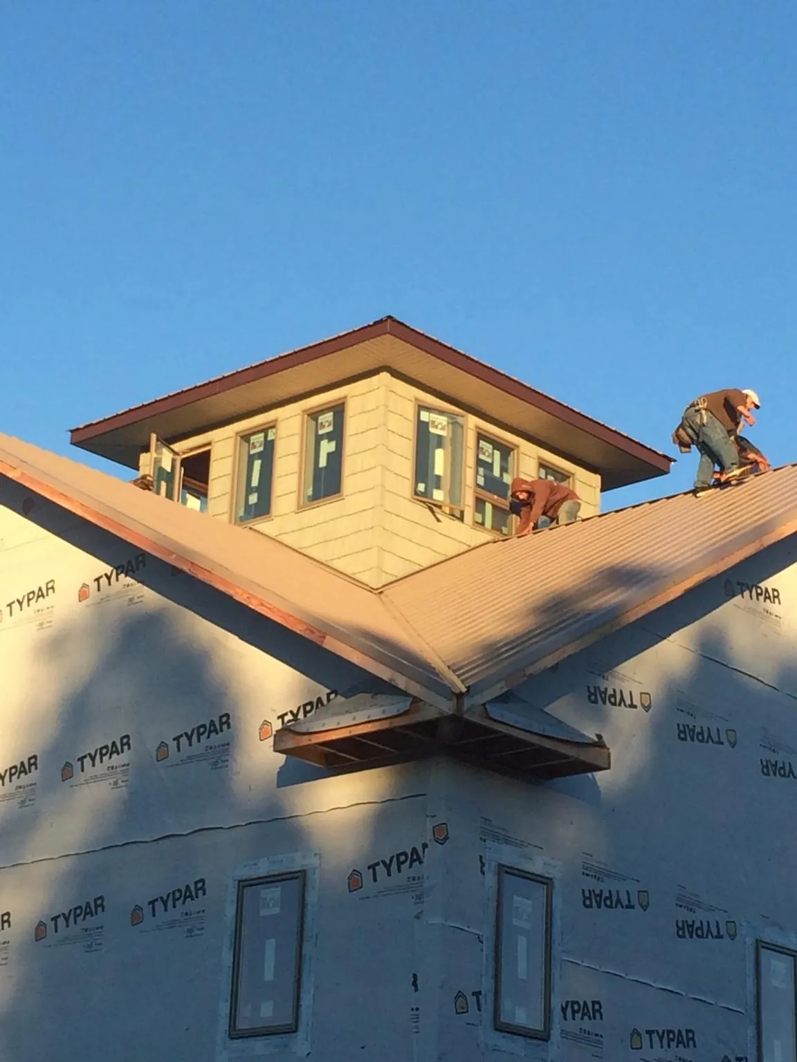 Roofers working around a rooftop cupola on a new metal roof at sunset — Roof Waterproofing in Hot Springs National Park by Roofing Brothers